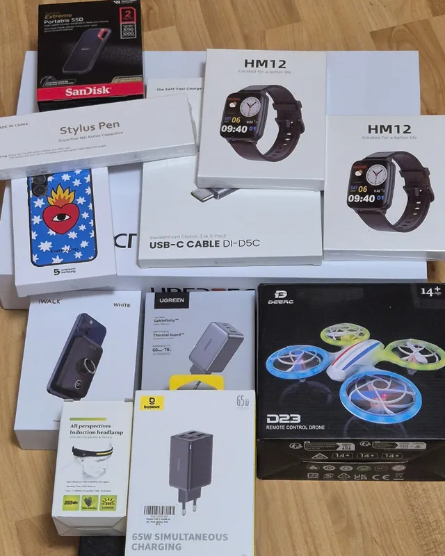 Cajas de cargadores, relojes, cable USB-C, un SSD y un dron sobre el suelo